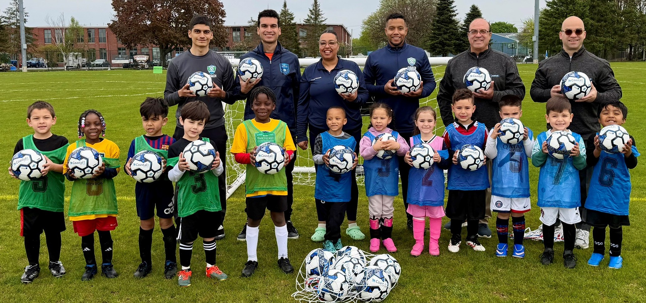 Group of kids and coaches with soccer balls